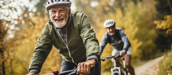 Tuinposter Two happy old mature people enjoying and riding bikes together to be fit and healthy outdoors. © Zie
