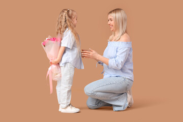 Little girl greeting her mother with tulips on beige background. International Women's Day celebration © Pixel-Shot