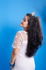 Beautiful young woman in white dress with shell tiara on her head with her back looking to the side.