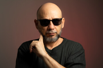Obraz premium White, bald man, wearing sunglasses, confident and serious looking towards the camera.