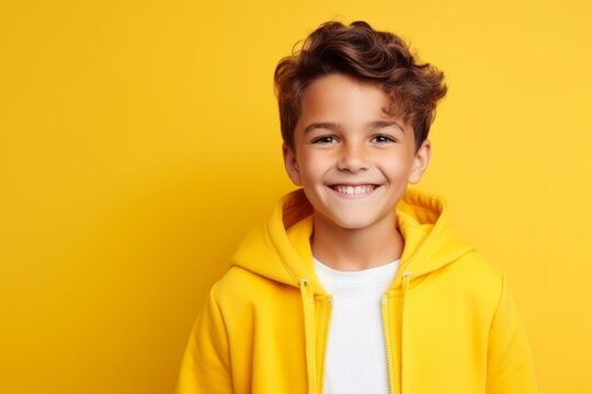 Portrait of a smiling little boy in yellow hoodie over yellow background