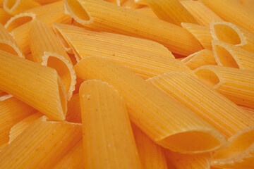 Close up of uncooked penne rigate pasta for background use. Dry macaroni noodles.