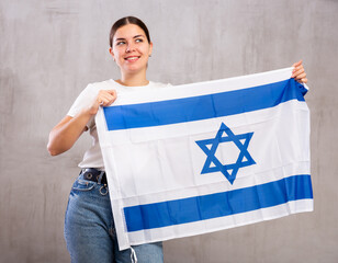 Joyful girl stands with flag of Israel. Isolated on gray background