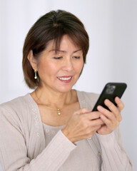 Smiling beautiful woman enjoying texting reading email on mobile phone relaxing standing bright...