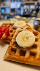 beautiful golden brown waffles covered in strawberries and banana slices with butter and syrup on a plate in Pasadena California USA