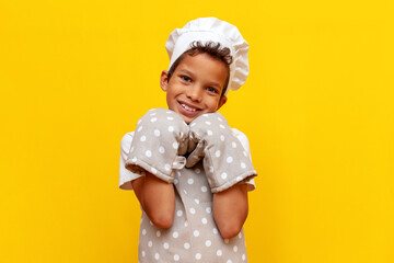boy african american baker in uniform and chef's hat on yellow isolated background, teenager child...