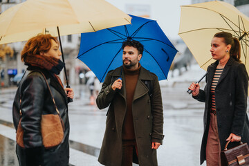 Business partners discussing a project outdoors on a rainy day under an umbrella, promoting collaboration and productivity.