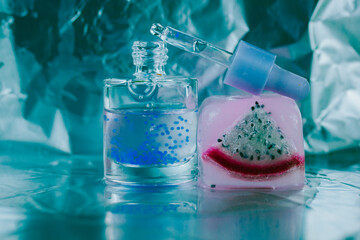 Cosmetic serum in glass pipette bottle on ice cube with pitaya dragon fruit inside. Natural cosmetics for facial skin care. Restorative oil for body.