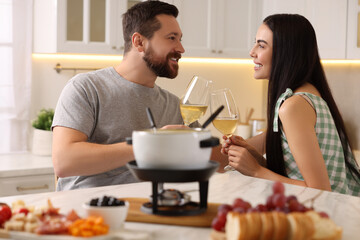 Romantic date with fondue. Couple clinking glasses of wine at home