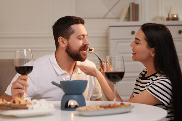Affectionate couple enjoying chocolate fondue during romantic date at home