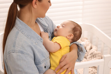 Fototapeta na wymiar Mother holding her sleeping newborn baby at home, closeup