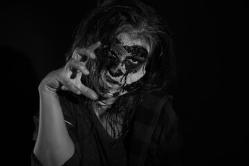 Scary zombie on dark background, black and white effect. Halloween monster