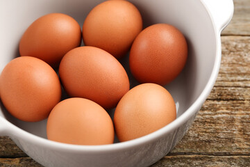 Unpeeled boiled eggs in saucepan on old wooden table, closeup
