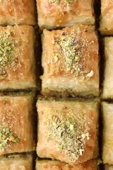 Delicious fresh baklava with chopped nuts as background, top view. Eastern sweets