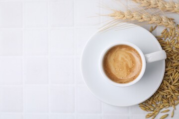 Cup of barley coffee, grains and spikes on white table, flat lay. Space for text