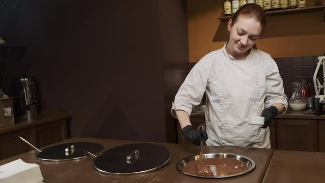 Lady chef pours melted dark chocolate into mug crafting beverage for chocolate enthusiasts closeup. Sweet drink for chocolate lovers
