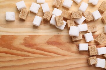 White and brown sugar cubes on wooden table, flat lay. Space for text