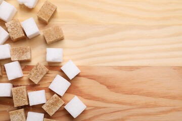 White and brown sugar cubes on wooden table, flat lay. Space for text