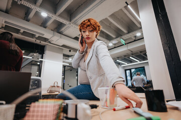 Businesswoman having phone call at the office while sitting on a working desk.