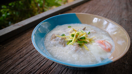 Close up Rice porridge ,congee with minced pork and ginger in white and blue bowl,Rice soup concept, on the wooden table