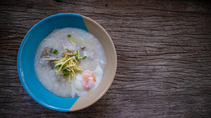 Close up Rice porridge ,congee with minced pork and ginger in white and blue bowl,Rice soup concept, on the wooden table