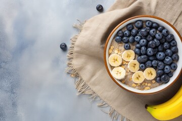 Obraz na płótnie Canvas Healthy oatmeal with bananas blueberries and walnut for breakfast or lunch Natural ingredients on a linen napkin with a cement background