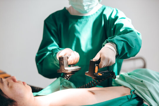 Professional expertise doctors, physician or surgeon in the operating room making CPR and use defibrillator electrical device to saving a patient life, Cardiac and heart attack, emergency and urgency.