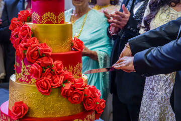 Indian couple's cutting a wedding cake close up