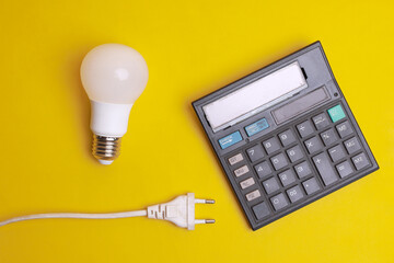 Calculator, LED light bulbs and electric plug on yellow background. Electricity cost saving...