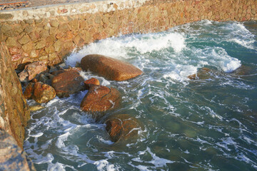 sea rocks next to the dock, sea water hitting the rocks