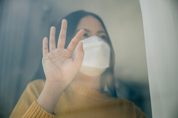 Obraz premium Depicting self-quarantine, Woman in a medical mask stays isolated at home emphasizing COVID-19 prevention during the outbreak situation and the concept of home quarantine.