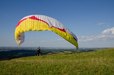 Man standing on field and exercising to maneuver his paraglider