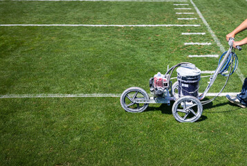 Painting the lines on a football field. Field painting machine at work putting down paint on the yard lines on the grass. American Football concept image