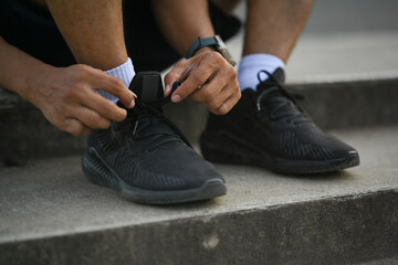 Cropped shot legs of sporty man tying shoelaces before jogging or cardio workout