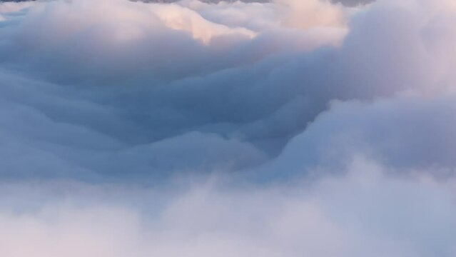 Scenic copy background with pastel blue clouds swirling fast, changing shape. Aerial over amazing cloudscape. Beautiful sky with gentle white clouds moving below. Time lapse above beautiful clouds 4K