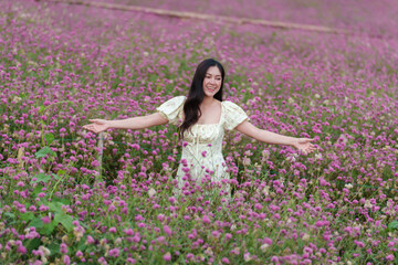 beautiful woman in dress enjoying blooming pink globe amaranth or bachelor button field