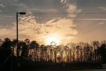 Sun setting behind the trees over a practice athletic field.