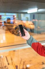 Close-up view of unrecognizable man using smartphone at airport check in window with casual clothes. People traveling with technology lifestyles