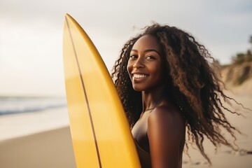 Portrait of a sexy young African American woman standing on the beach and holding surfboard.