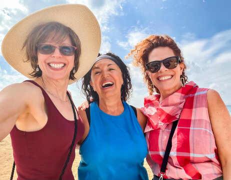 Three laughing women friends tourists selfie blue sky beach background