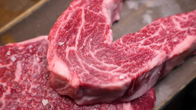 숯불에 구운 마블링 좋은 숙성 한우 알등심과 새우살을 집게로 잡고 부드럽게 찢는 모습