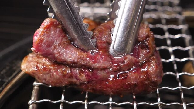 맛있게 구워진 한우 두조각을 집게로 누르자 뿜어져나오는 육즙