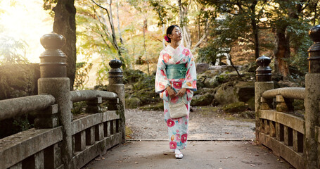 Walking, traditional and Japanese woman in park for calm, fresh air and relax on bridge outdoors. Travel, culture and person in indigenous clothes, style and kimono on holiday, peace or thinking