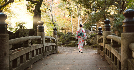 Bridge, walking and Japanese woman in park for wellness, fresh air and relaxing in nature. Travel,...