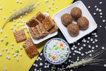 Indian traditional sweets for Makar sankrant festival called Tilgul Laddoo or sesame and Jaggery Laddu Till Tikiya and colourful halwa 