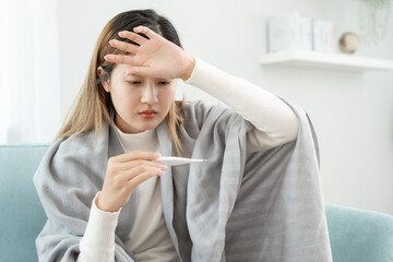 Young Asian woman having high fever while checking body temperature, female sneezing and runny nose...