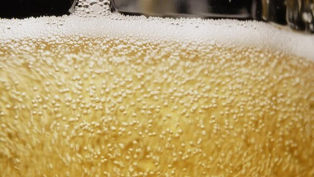 Macro closeup footage of pour the golden yellow beer bottle to glass with beer bubbles float to top