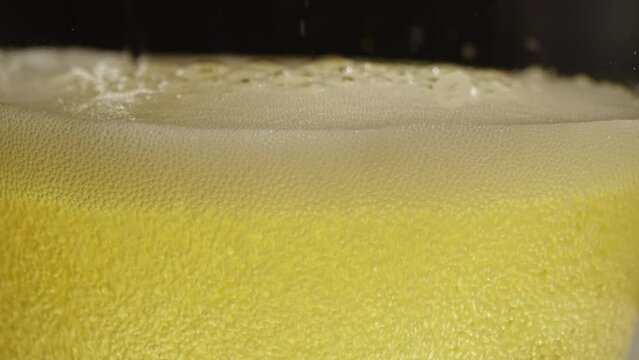 Macro closeup footage of pour the golden yellow beer bottle to glass with beer bubbles float to top