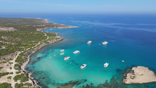 Flying over yachts with tourists in the blue lagoon on the west coast of Cyprus. Turquoise lagoon water in AKAMAS Nature Reserve Park, Cyprus. Aerial shot, 4K