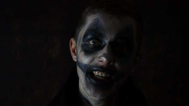 Halloween makeup Caucasian man talking scary performance in front of a black background dark clown